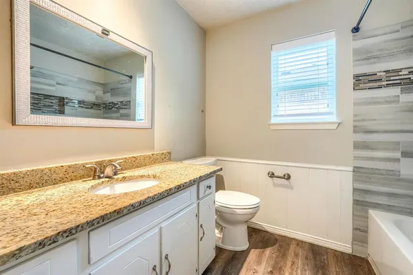 a bathroom with a granite countertop sink mirror vanity and toilet