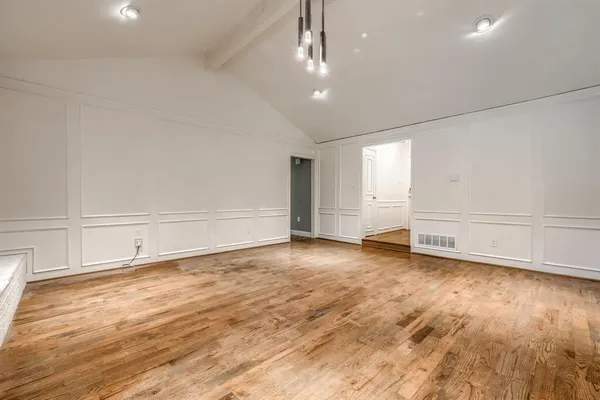 an empty room with wooden floor and white walls