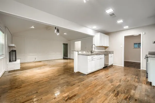 a large kitchen with cabinets and a wooden floor