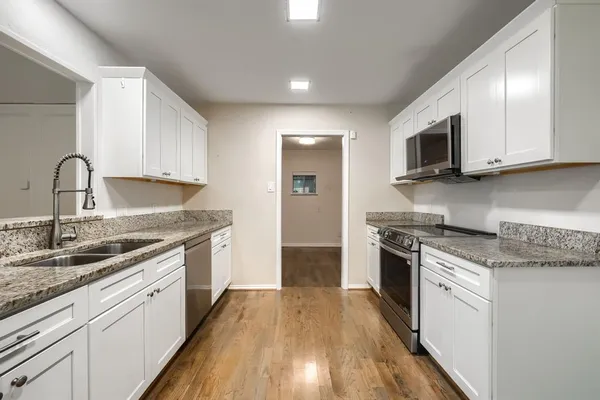 a kitchen with stainless steel appliances granite countertop wooden cabinets a stove top oven a sink and dishwasher