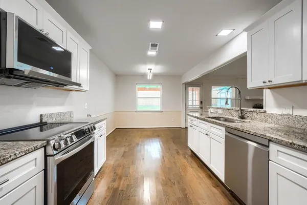 a kitchen with stainless steel appliances granite countertop a stove a sink and a microwave