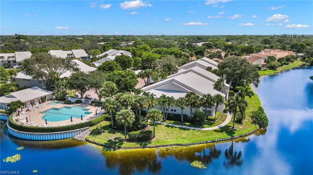 793 Willowbrook Drive, Unit 104 Naples, FL 34108 - Photo 12 of 38 a view of a swimming pool with lawn chairs under an umbrella