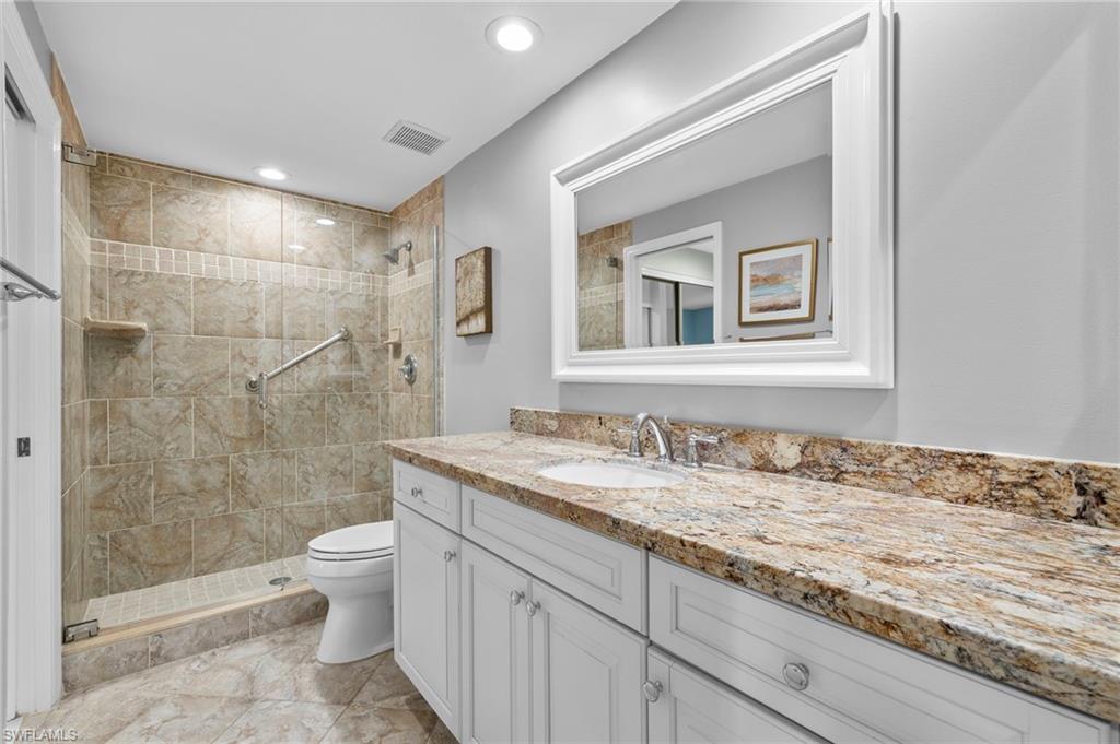 793 Willowbrook Drive, Unit 104 Naples, FL 34108 - Photo 22 of 38 a bathroom with a granite countertop sink a toilet and shower