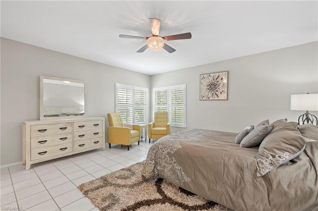 793 Willowbrook Drive, Unit 104 Naples, FL 34108 - Photo 23 of 38 a bedroom with a bed and a chandelier