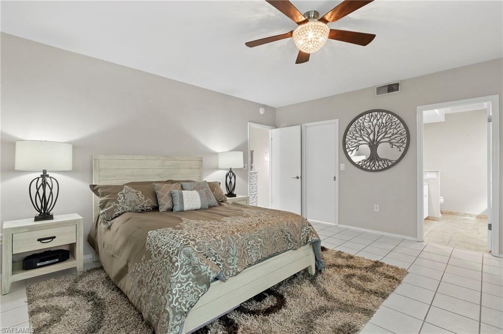 793 Willowbrook Drive, Unit 104 Naples, FL 34108 - Photo 31 of 38 a bedroom with a large bed and a chandelier