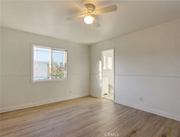 an empty room with wooden floor ceiling fan and windows