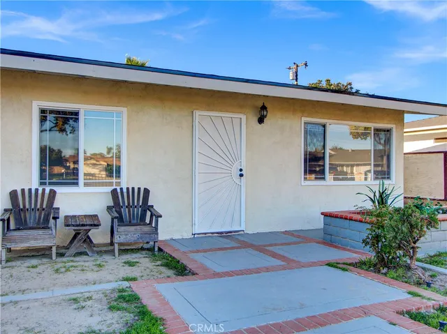 a patio with a table and chairs and potted plants