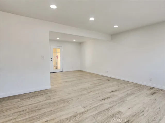 an empty room with wooden floor and natural light