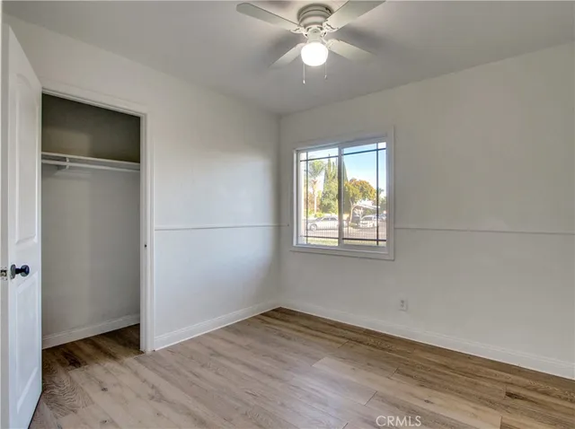 an empty room with wooden floor closet and windows