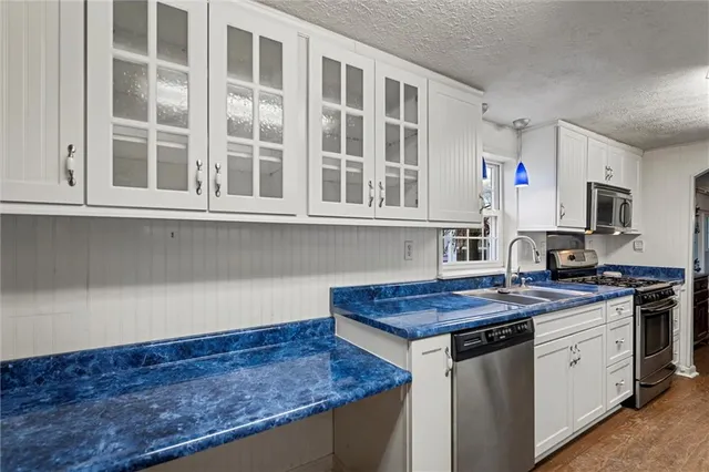 a kitchen with stainless steel appliances granite countertop a stove a sink and a microwave