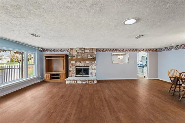 a view of empty room with fireplace and wooden floor