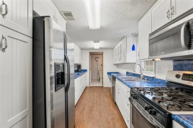 a kitchen with stainless steel appliances granite countertop a stove top oven a sink dishwasher a refrigerator and cabinets with wooden floor