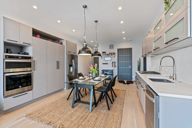 1708 West Cermak Road, Unit 2E Chicago, IL 60608 - Photo 18 of 49 a kitchen with stainless steel appliances kitchen island granite countertop a sink a stove a refrigerator and island with wooden floor