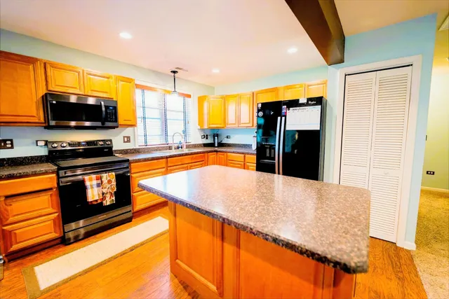 a kitchen with stainless steel appliances granite countertop a refrigerator a stove top oven and a sink with granite countertops