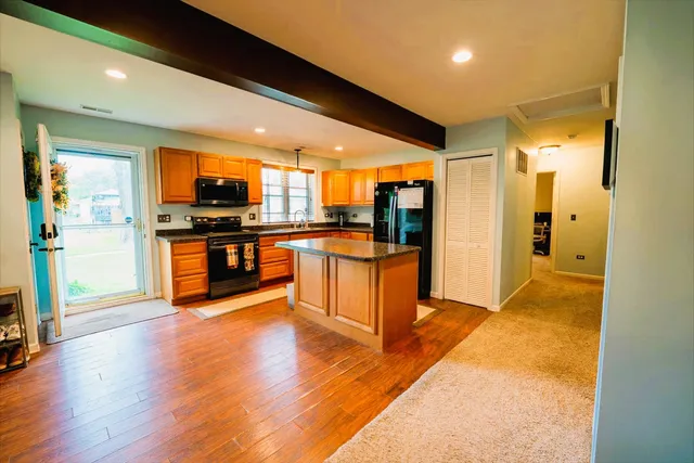 a large kitchen with stainless steel appliances granite countertop a large counter top and a wooden floors