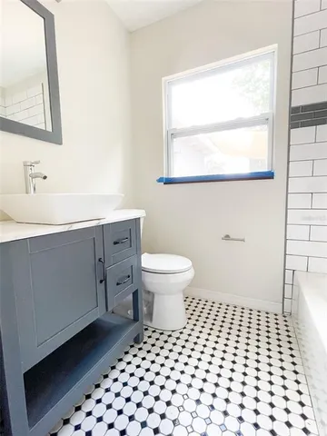 a bathroom with a sink a toilet a window and mirror