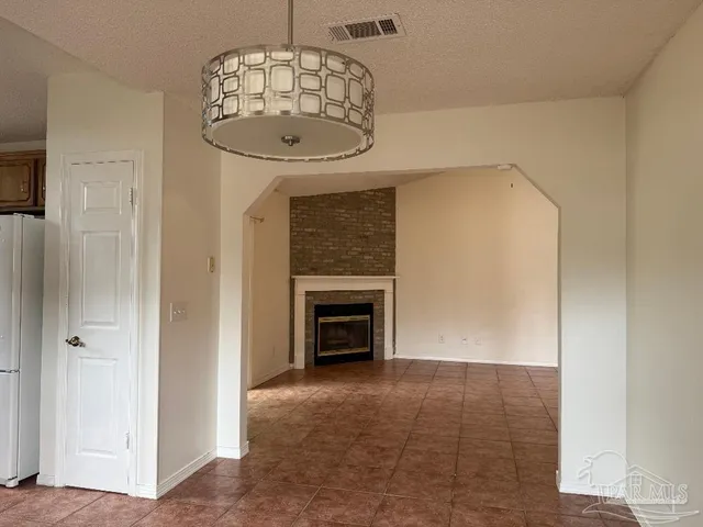 an empty room with a fireplace and chandelier