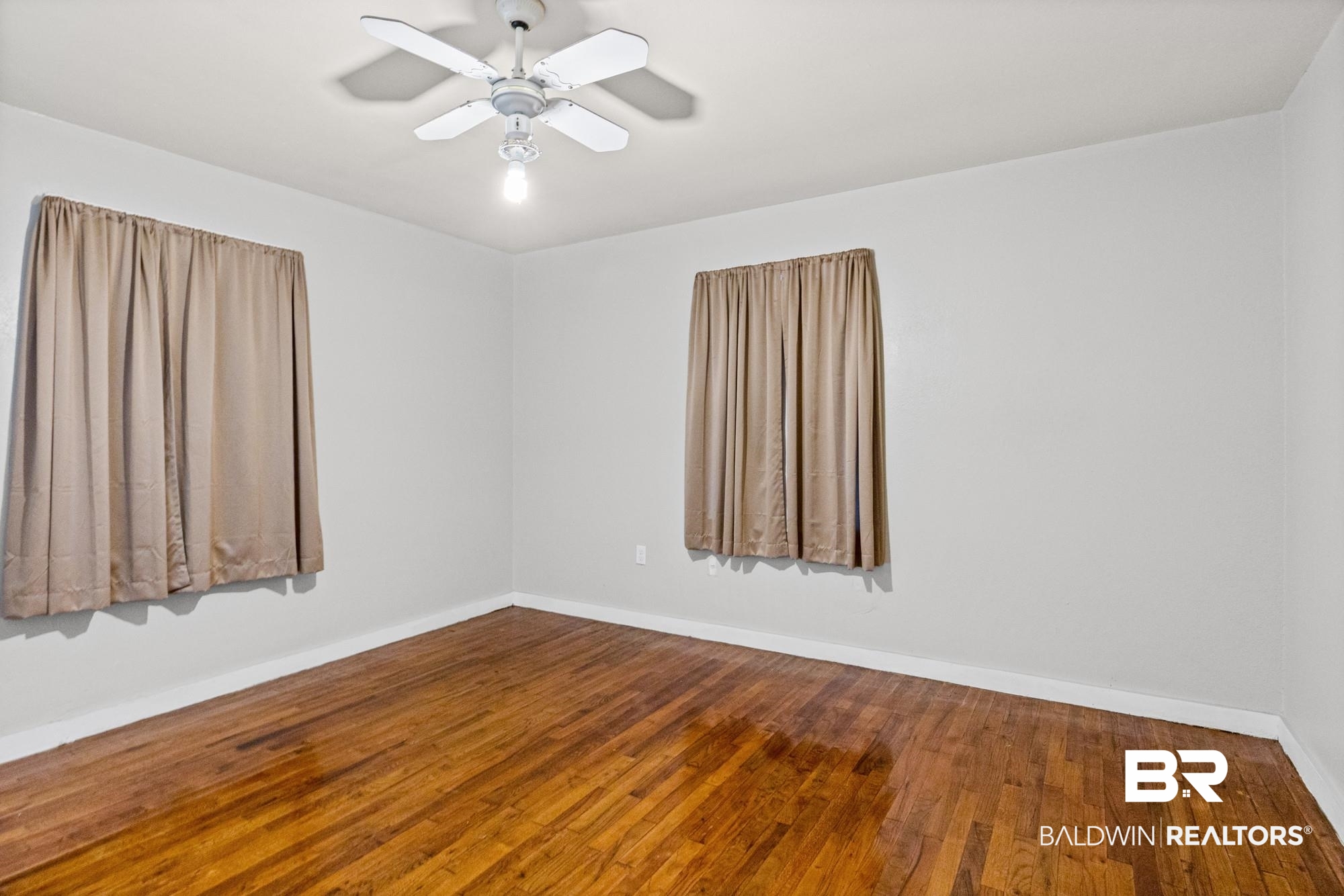 312 Sutherland Drive Mobile, AL 36611 - Photo 13 of 28 Unfurnished primary bedroom featuring wood-finish flooring, light-colored walls, and a ceiling fan with integrated lighting