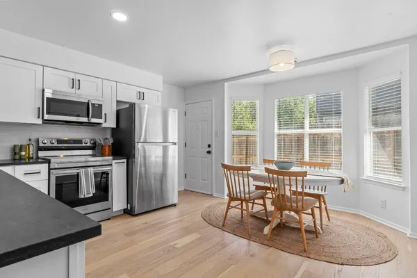 a kitchen with stainless steel appliances a dining table chairs stove refrigerator and microwave