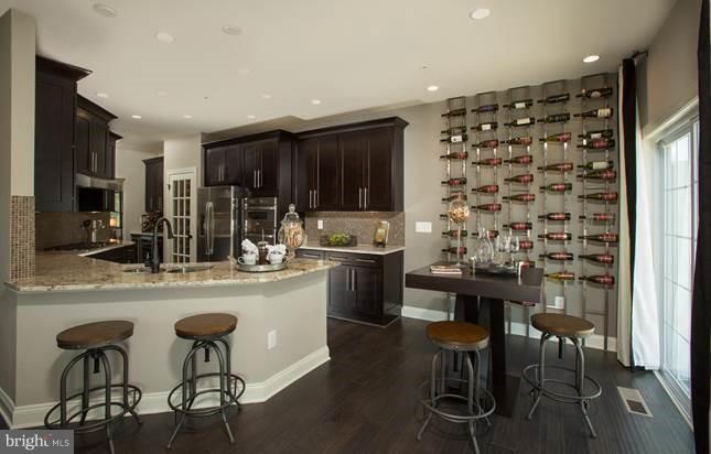 7682 Elmcrest Road Hanover, MD 21076 - Photo 9 of 21 a kitchen with a dining table chairs cabinets and stainless steel appliances