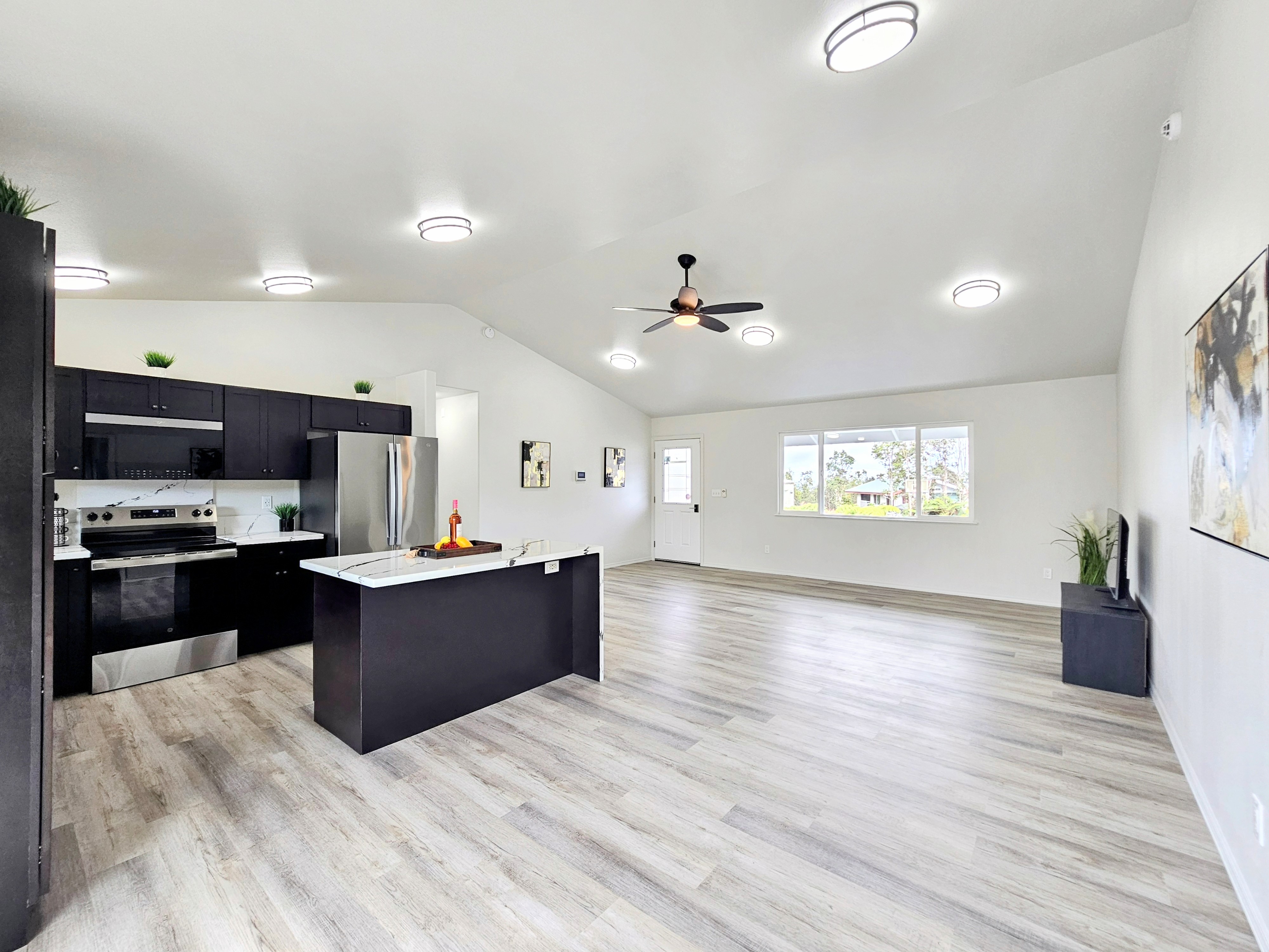 11-3385 Old Volcano Road Volcano, HI 96785 - Photo 10 of 30 a large kitchen with stainless steel appliances kitchen island granite countertop a stove top oven a sink dishwasher and wooden floor