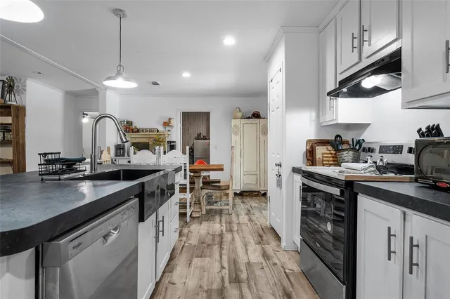 a kitchen with granite countertop a sink a counter space appliances and cabinets