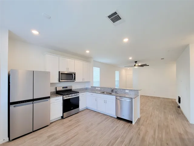 a kitchen with stainless steel appliances a refrigerator a stove top oven a sink and cabinets