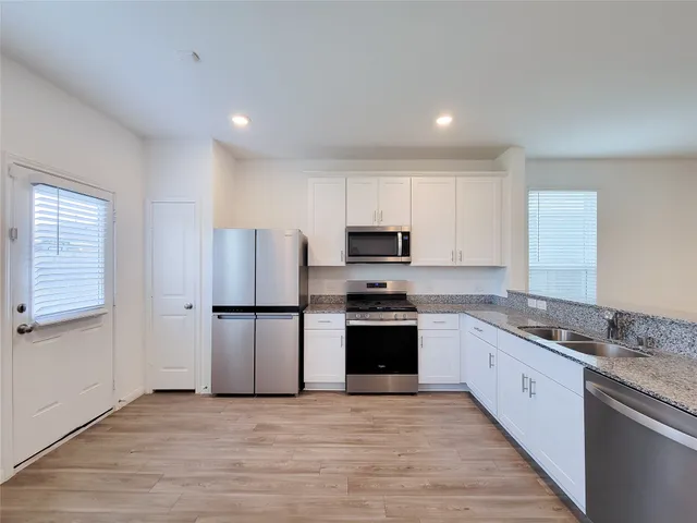 a kitchen with stainless steel appliances a refrigerator a stove top oven a sink and cabinets