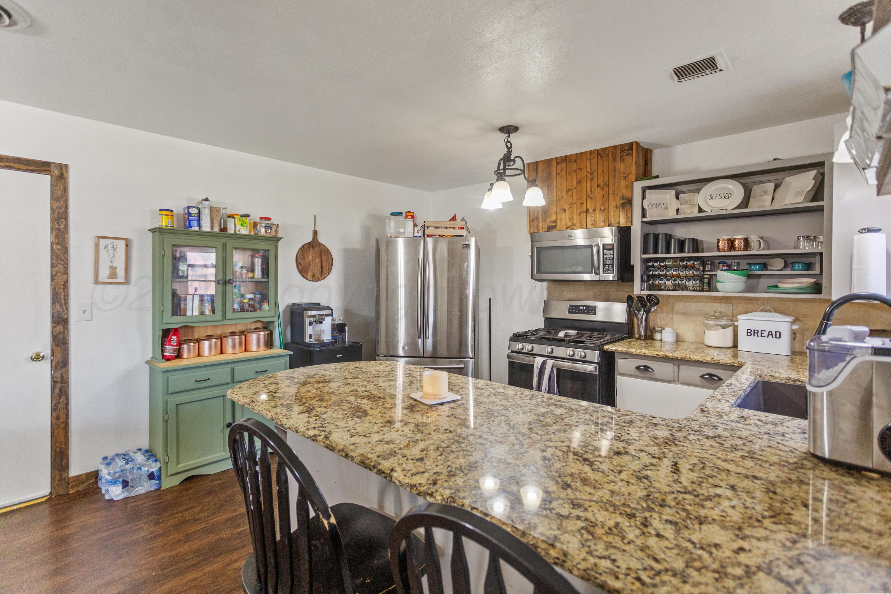 920 South Madden Street Shamrock, TX 79079 - Photo 14 of 39 a kitchen with stainless steel appliances granite countertop a stove top oven a sink a dining table and chairs