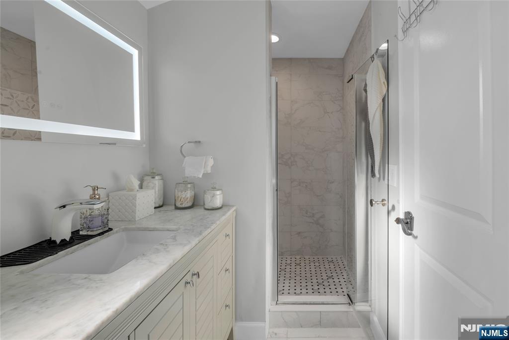170 Tenafly Road Englewood, NJ 07631 - Photo 23 of 40 a bathroom with a granite countertop sink mirror and shower