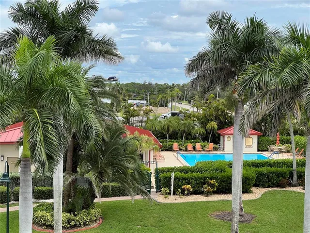 a view of a house with a big yard and palm trees