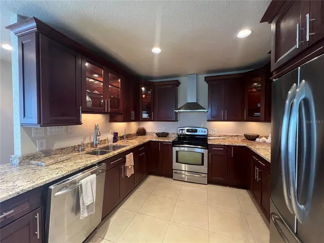 a large kitchen with stainless steel appliances granite countertop a sink stove and refrigerator