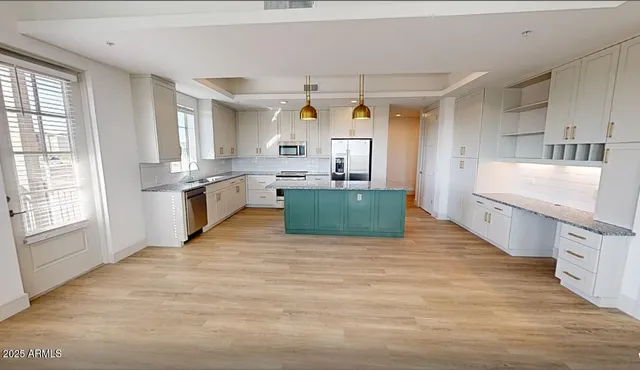 a large kitchen with kitchen island a stove a sink dishwasher and white cabinets with wooden floor