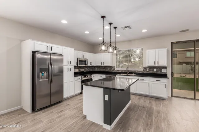 a kitchen with stainless steel appliances granite countertop a refrigerator a sink and a stove