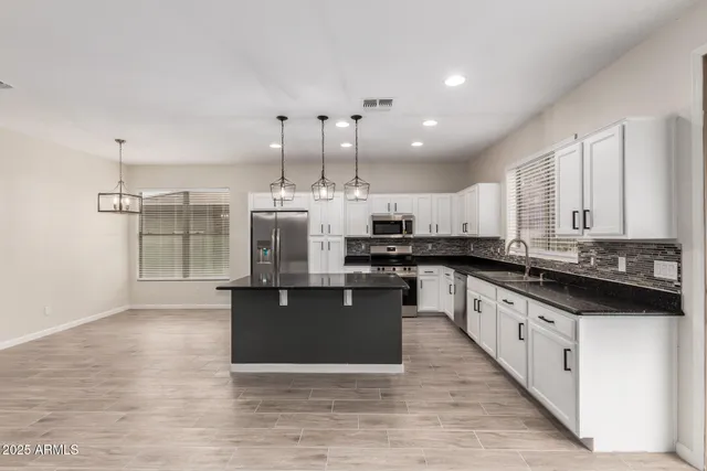 a large kitchen with stainless steel appliances kitchen island granite countertop a large counter top a stove a sink and a refrigerator