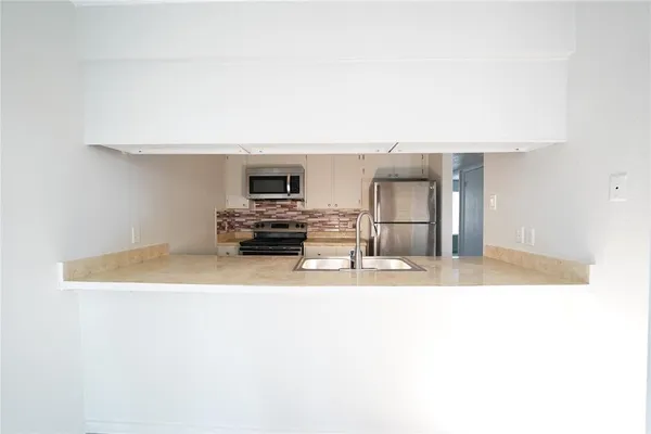 a view of kitchen with wooden cabinet and refrigerator