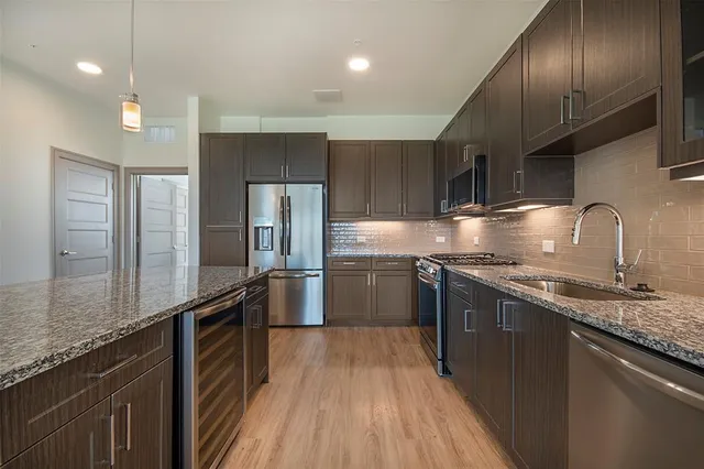 a large kitchen with granite countertop a large counter top a sink stainless steel appliances and cabinets