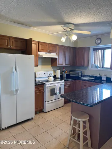 a kitchen with granite countertop a stove a sink and a refrigerator