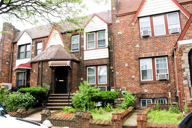 a front view of a brick house with a yard and potted plants