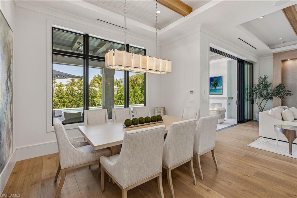 529 Neapolitan Way Naples, FL 34103 - Photo 8 of 26 a dining room with furniture wooden floor a potted plant and windows