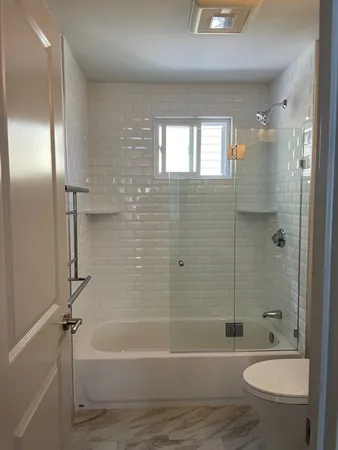 a bathroom with a granite countertop bathtub shower sink vanity and toilet