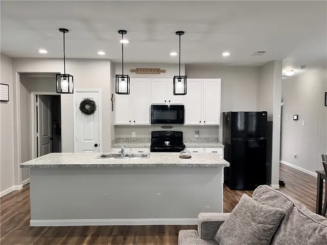 a kitchen with granite countertop a sink a counter top space appliances and cabinets