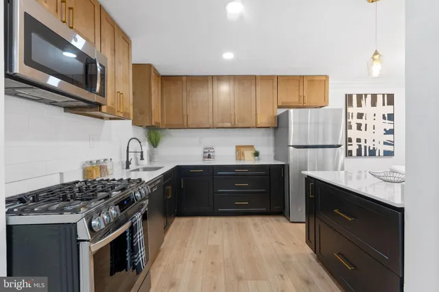 a kitchen with stainless steel appliances granite countertop a stove top oven a refrigerator a sink and dishwasher with wooden floor