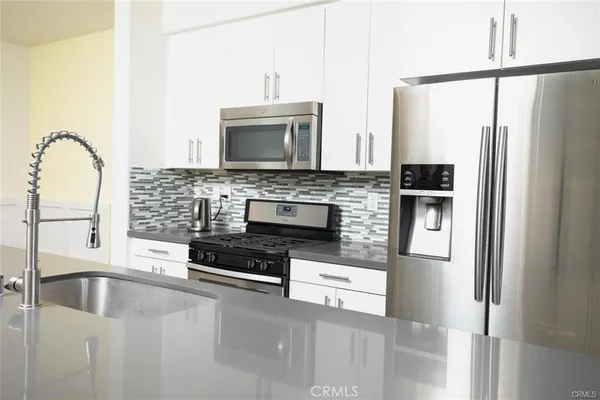 a kitchen with stainless steel appliances granite countertop a refrigerator a stove and a sink with wooden floor