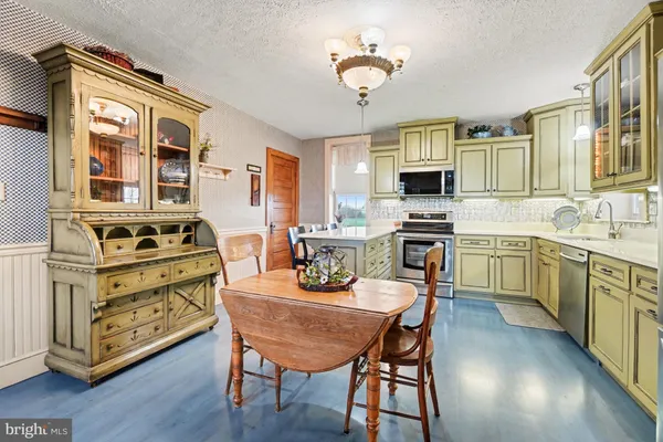 a kitchen with a stove a sink dishwasher a dining table and chairs with wooden floor