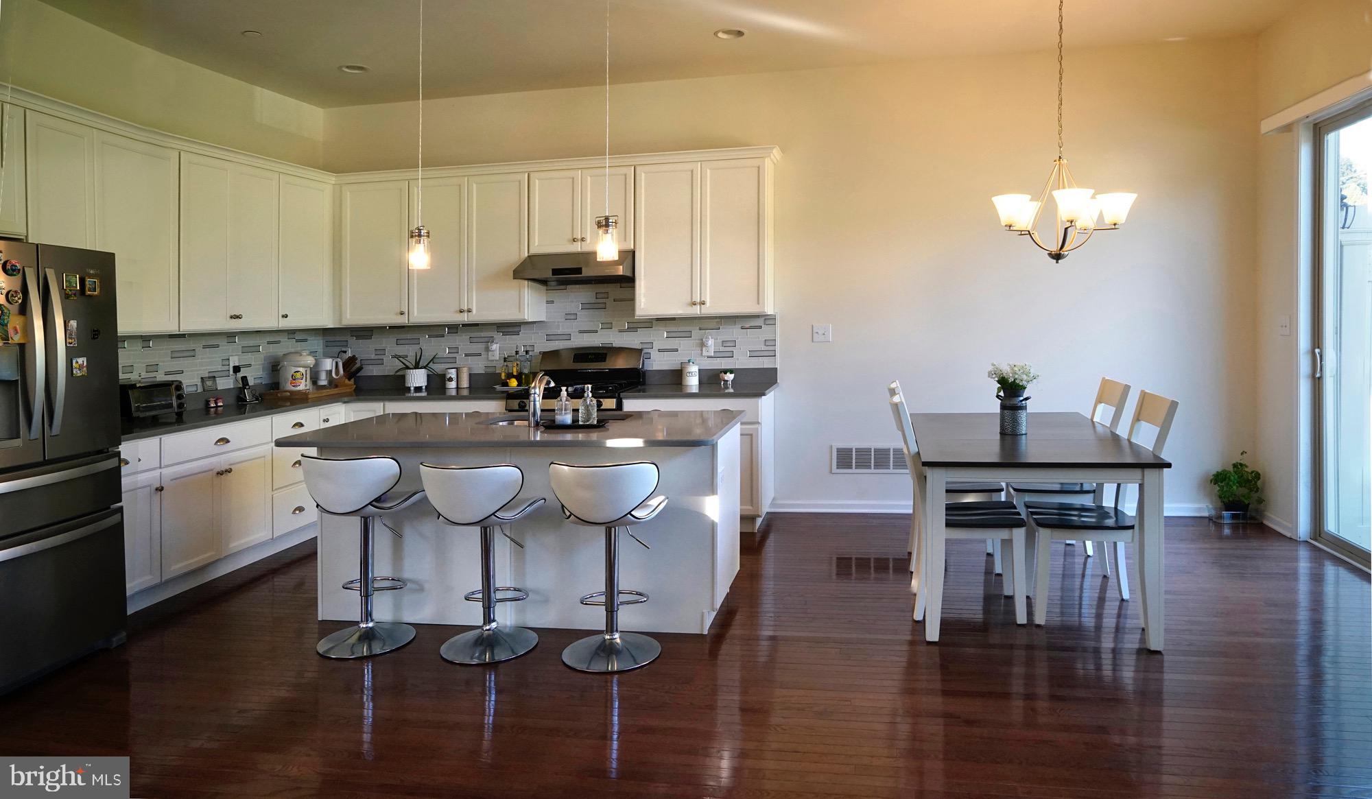 29 Chasmere Drive Kennett Square, PA 19348 - Photo 8 of 21 a kitchen with stainless steel appliances granite countertop a stove a refrigerator a sink a dining table and chairs with wooden floor