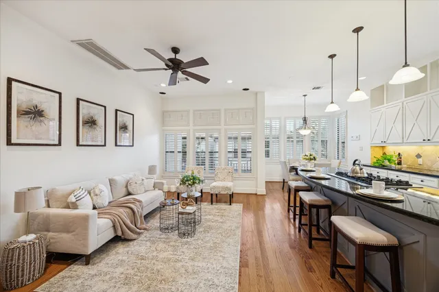 a living room with furniture kitchen view and a wooden floor