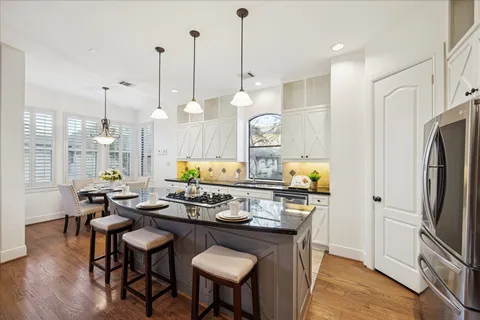 a kitchen with stainless steel appliances granite countertop a stove a sink dishwasher a refrigerator white cabinets and wooden floor