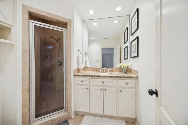a bathroom with a granite countertop sink a mirror and a shower