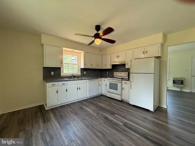 a kitchen with kitchen island white cabinets a sink a window and stainless steel appliances